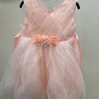 Pink dress with floral embellishment on a hanger against a plain background