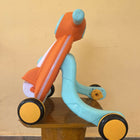 Colorful children's balance bike on a wooden surface with a yellow wall background