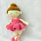 Crocheted doll with a pink dress and brown hat on a white background