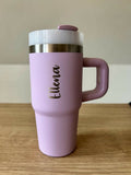Pink travel mug with a handle on a wooden surface