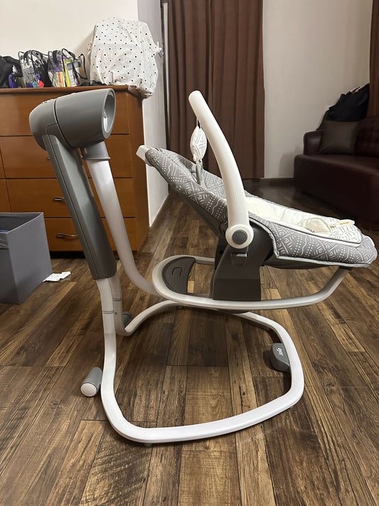 Baby swing on a wooden floor with furniture in the background