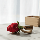 Red strawberry-shaped teething ring with a wooden tag labeled 'BAVIKNIT' on a light wooden surface.