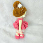 Crocheted doll with a brown hat and pink dress on a white background
