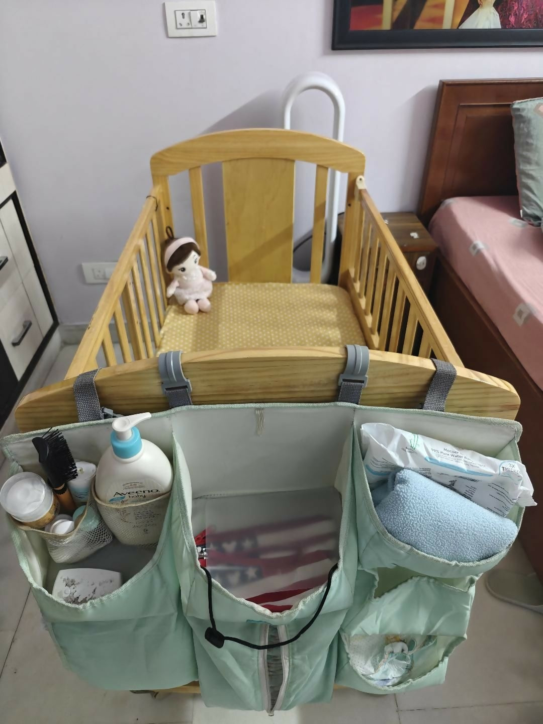 Baby crib with a hanging organizer containing baby care items in a room setting.