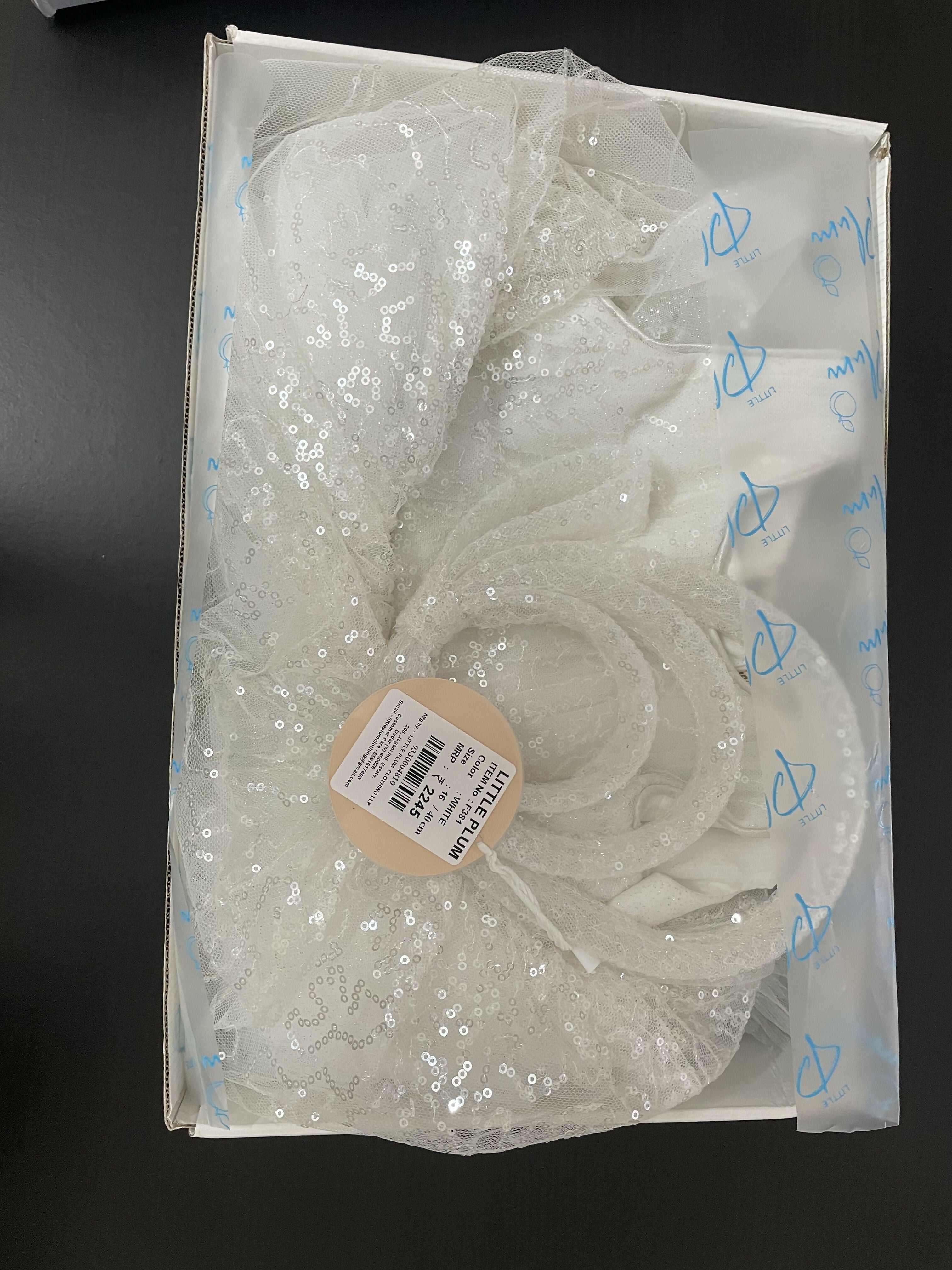 White sequin dress in a clear plastic bag on a black background