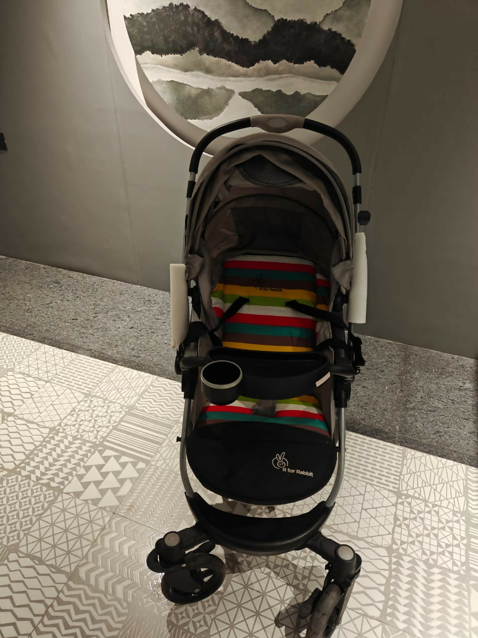 Stroller with colorful patterned mat on a tiled floor