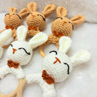 Set of crochet bunny rattle toys with wooden rings on a soft surface