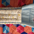 Baby crib with mattress and pillow on a colorful quilted blanket
