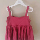 Pink tank top with straps on a white hanger against a beige background