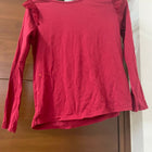 Red long-sleeve top on a hanger against a wooden door background