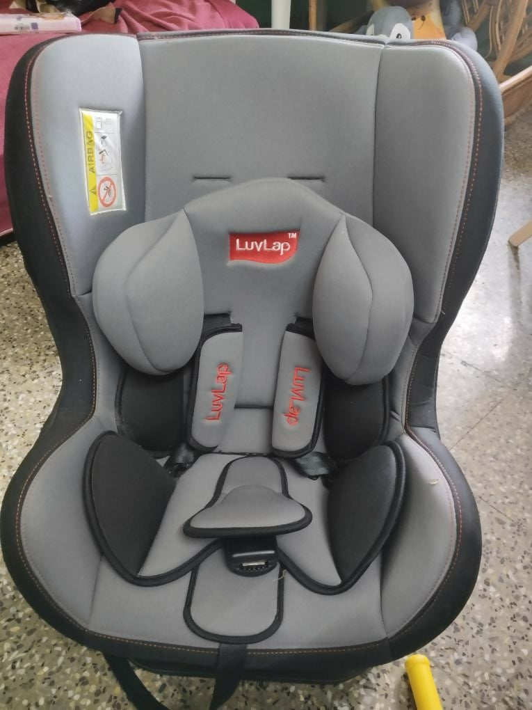 Gray and black car seat with LuvLap branding on a concrete floor.