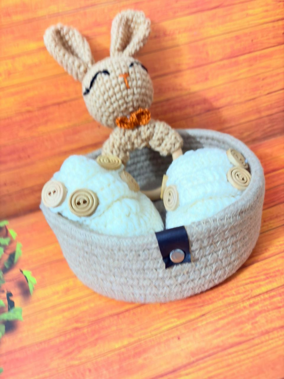 Small crochet rabbit toy sitting inside a round basket on a wooden surface