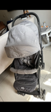 Gray stroller on a tiled floor with a table and chairs in the background
