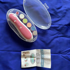 Pink nail clipper with colorful nail pads and instruction sheet on a blue fabric background