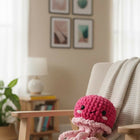 Pink crochet octopus toy on a chair with a cozy living room background