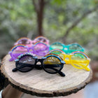 Colorful sunglasses on a wooden surface with a blurred natural background