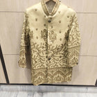 Decorative jacket with intricate patterns on a hanger against a neutral background