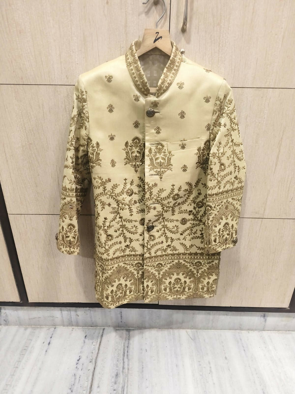 Decorative jacket with intricate patterns on a hanger against a neutral background