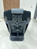Black car seat on a tiled floor with a wooden door in the background
