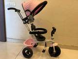 Pink and black baby tricycle on a light-colored floor.