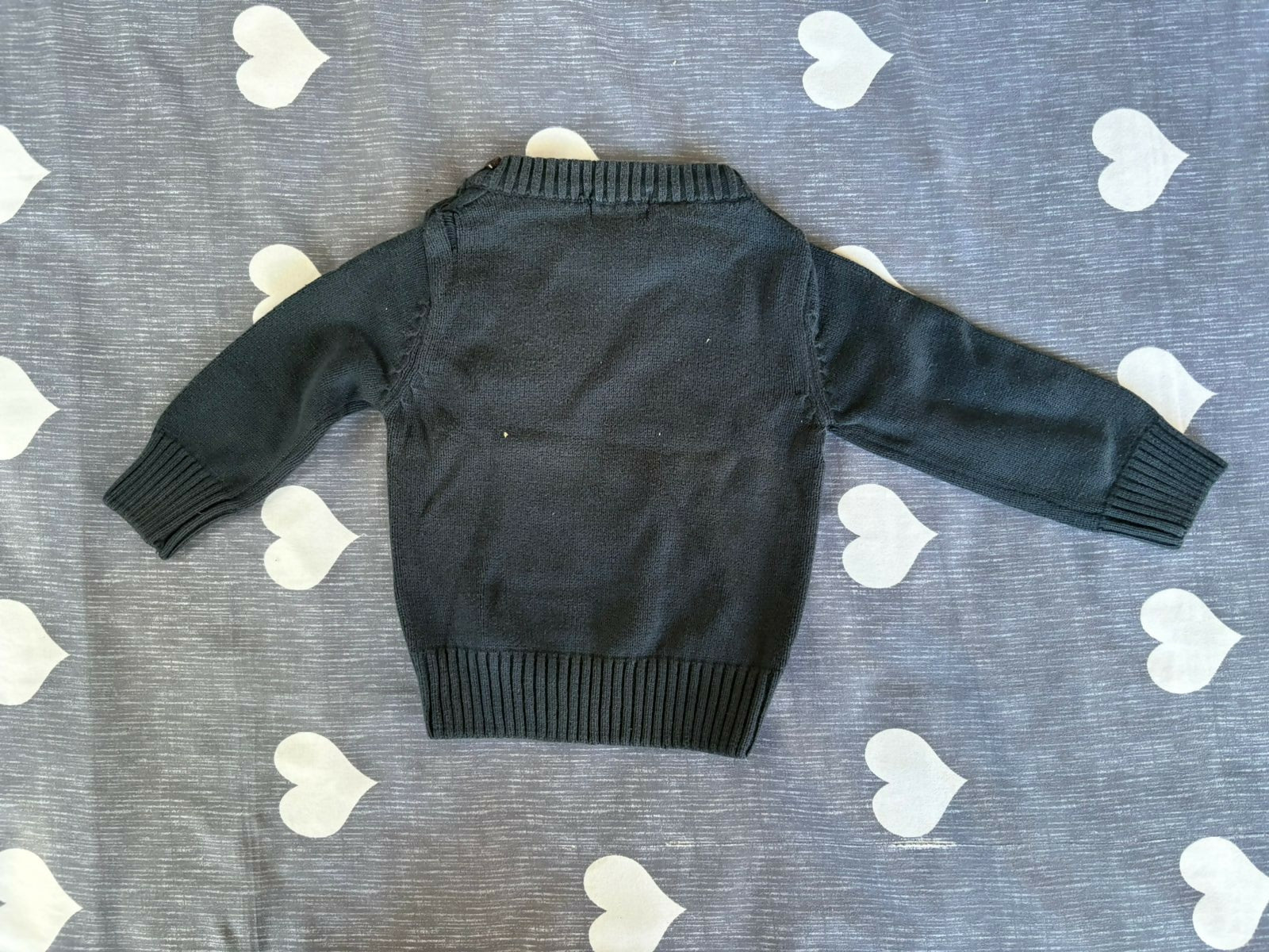 Black sweater on a gray surface with white heart patterns
