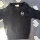 Black sweater with a logo on a gray surface with heart patterns