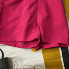 Pink shorts with a wooden ring on a patterned fabric background