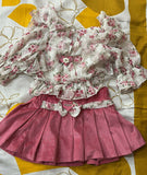 Floral top and pink skirt set on a patterned fabric background
