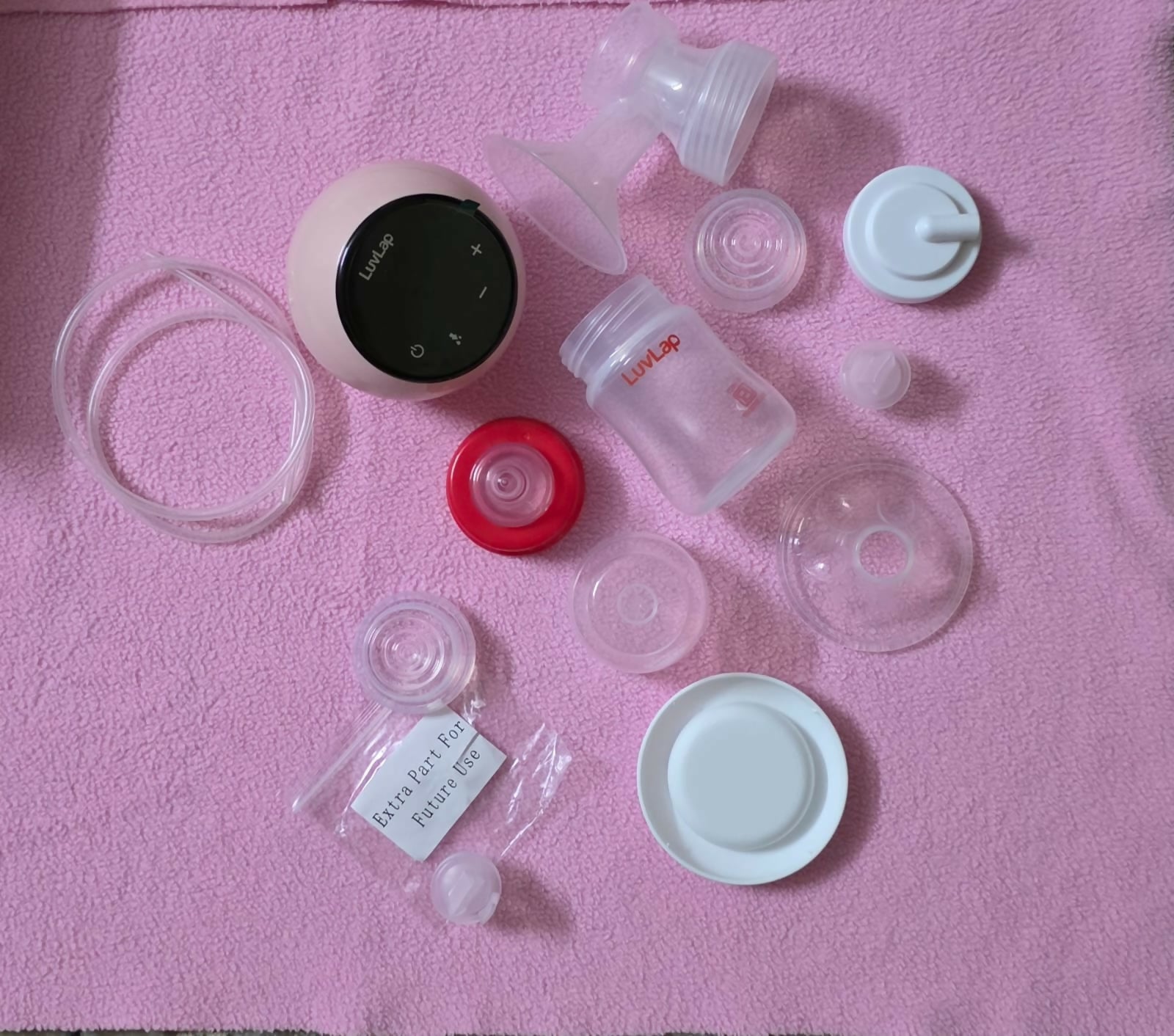 Breast pump parts and accessories on a pink surface