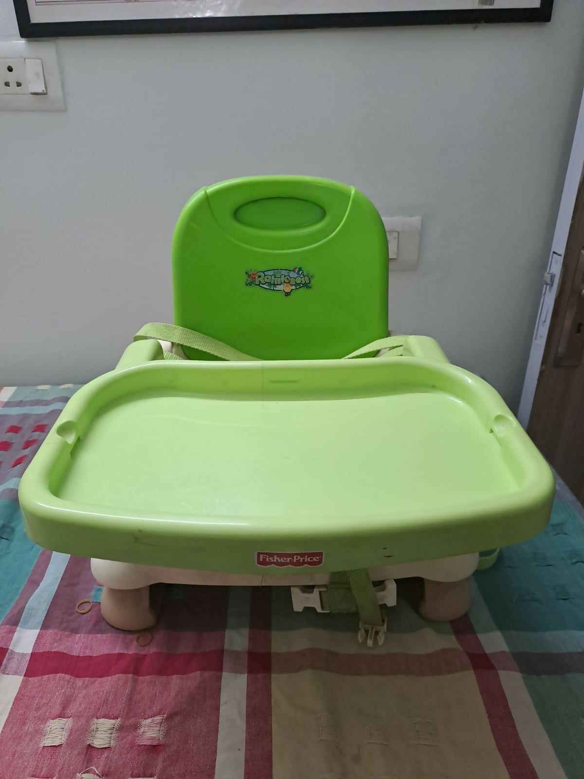Green high chair on a checkered floor with a white wall background