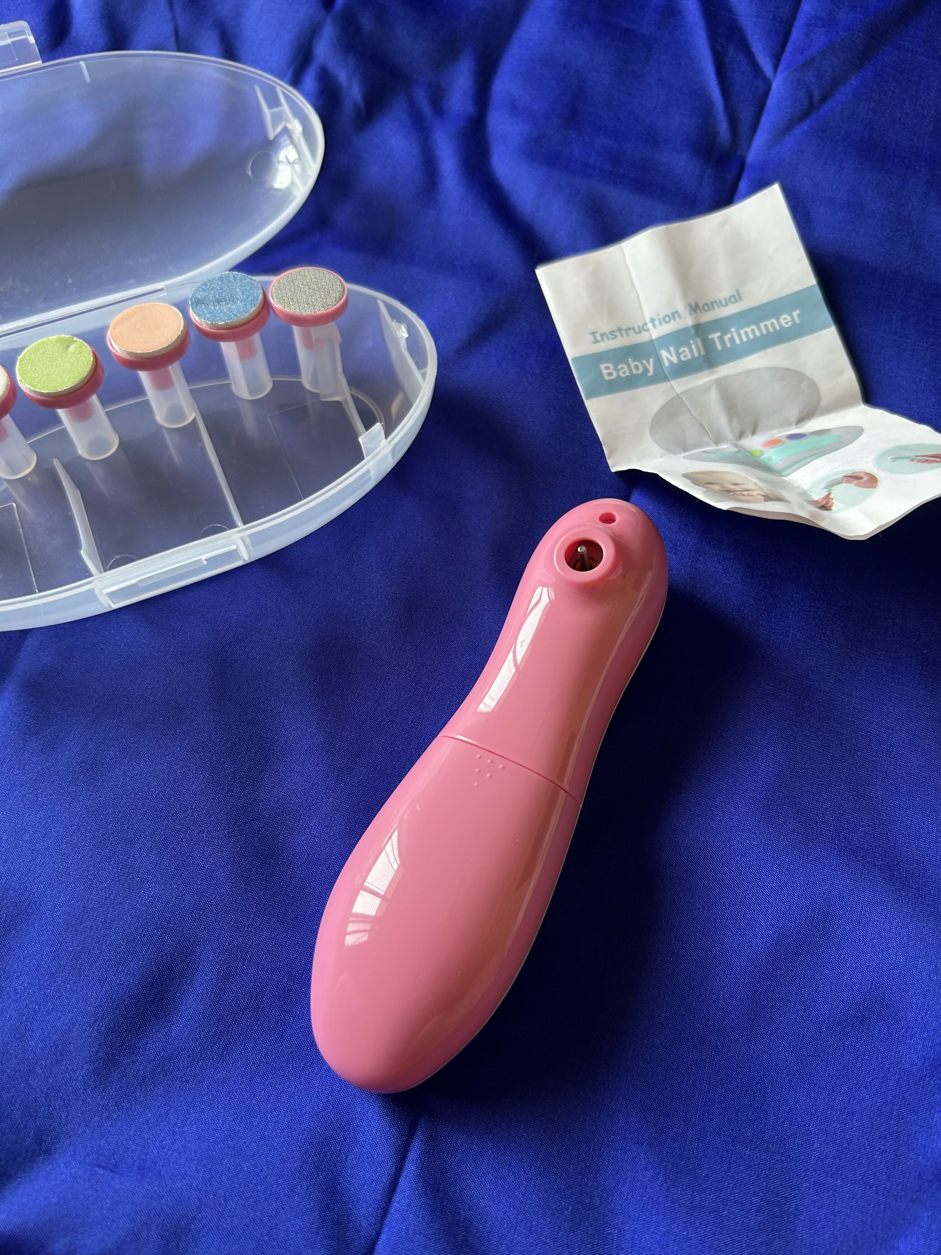 Pink baby nail trimmer with a clear container and instructions on a blue background