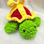 Crocheted turtle toy with a crown on a white background