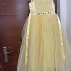 Yellow dress with floral details on a hanger against a wooden door background