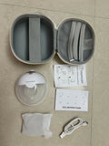 Product packaging with a round case, device, USB cable, and manuals on a beige surface.