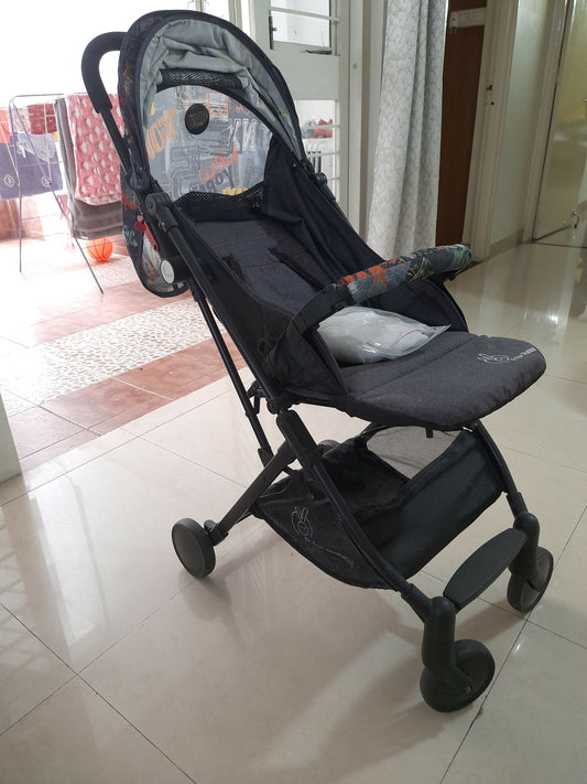 Black stroller on a tiled floor with a blurred background