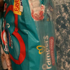 Pack of Pampers baby diapers with a price tag on a textured surface