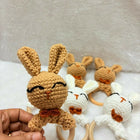 Set of crochet bunny toys with wooden rings on a textured surface
