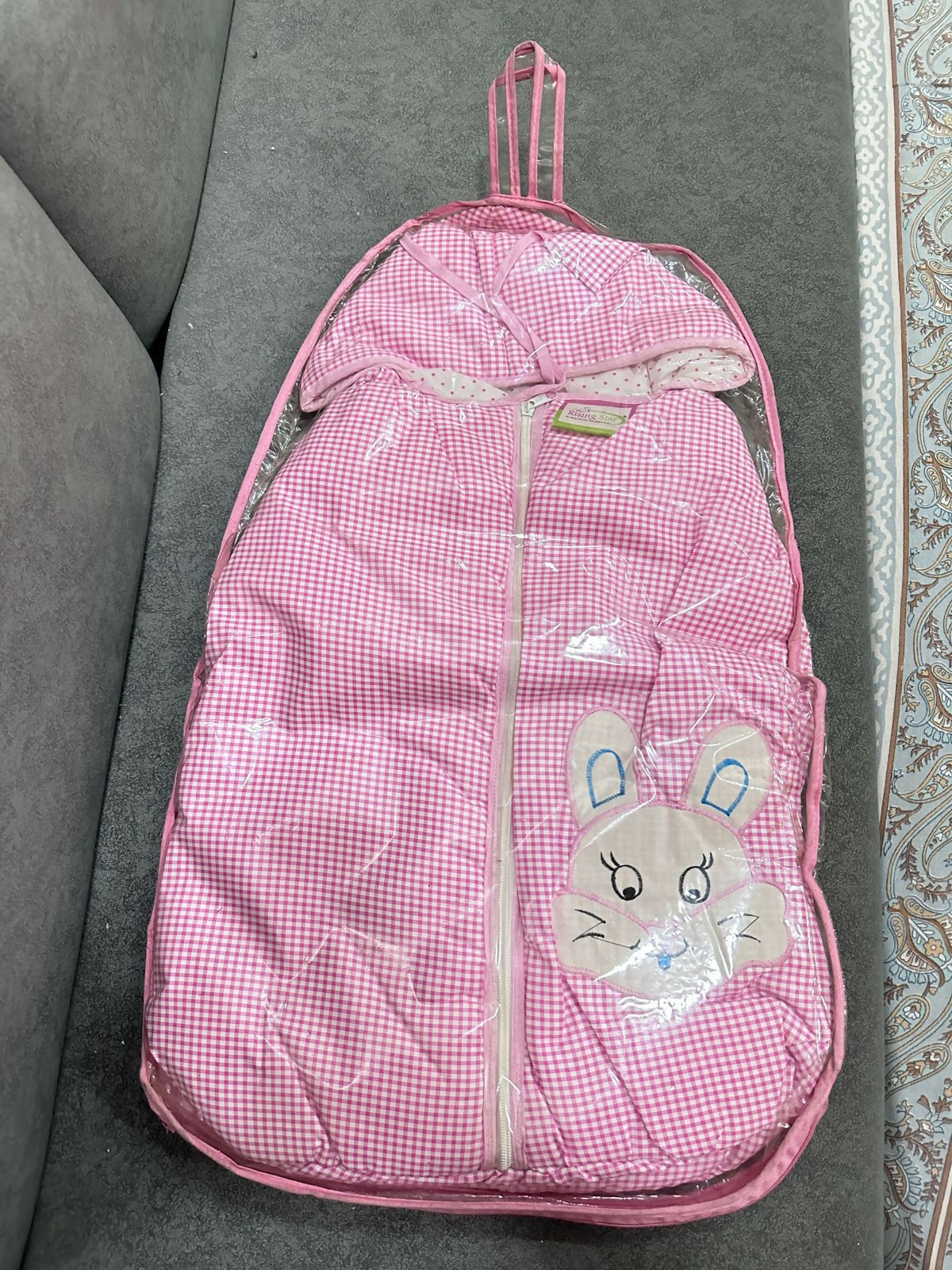 Pink checkered backpack with a cartoon bunny design on a gray surface
