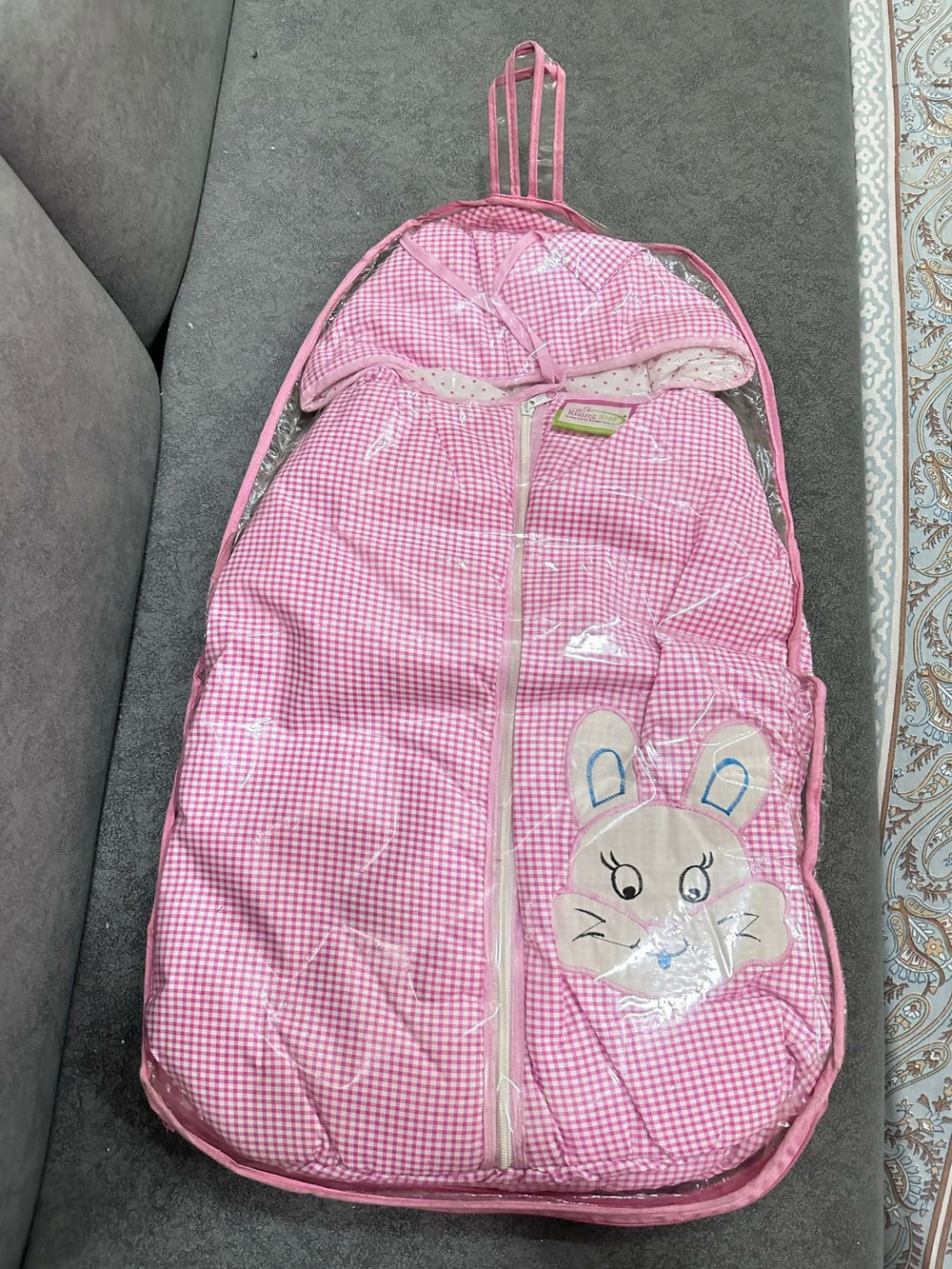Pink checkered backpack with a cartoon bunny design on a gray surface