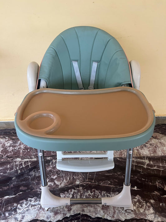 Green and beige high chair on a marble floor with a yellow wall background