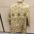 Embroidered traditional jacket on a hanger against a light wooden panel background