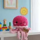 Pink crochet octopus toy on a shelf with colorful toys and a framed picture in the background.