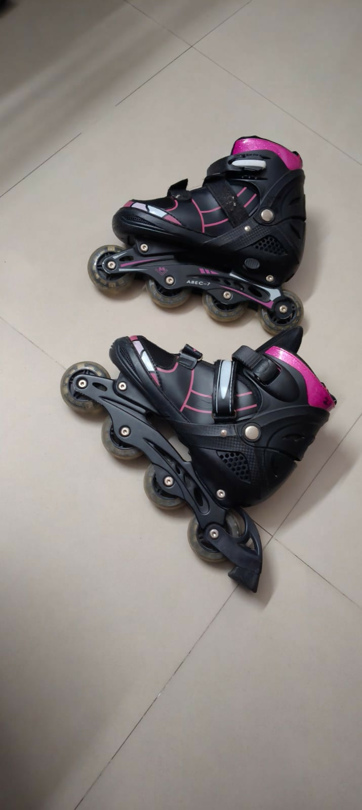 Pair of black and pink inline skates on a tiled floor