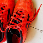 Red athletic shoes with black soles on a white surface