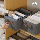 Gray storage bins with handles containing folded clothes inside a wooden drawer, brand 'TULSI' visible.