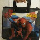 Spider-Man bag with a person holding it against a white wall.