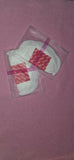 White product in a clear plastic bag with red label on a pink background