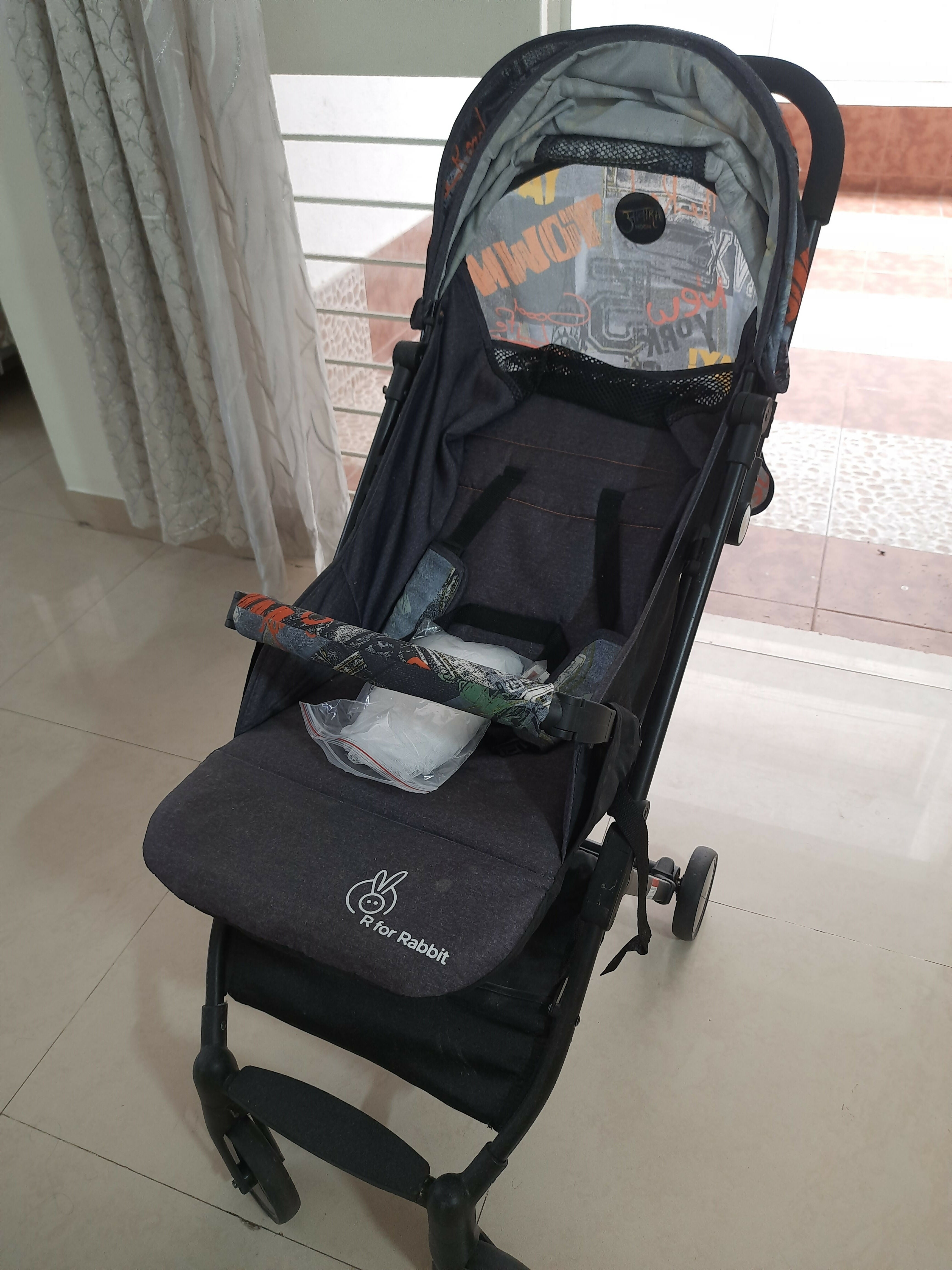 Black baby stroller with colorful design on a tiled floor