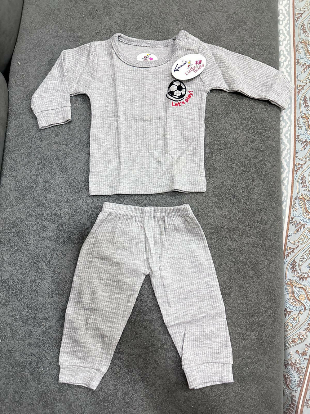Gray baby outfit with long-sleeve top and pants on a textured surface