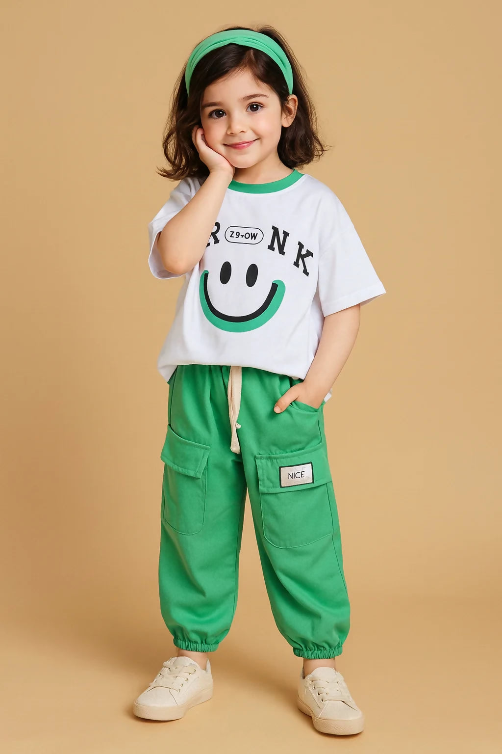 Child wearing a white t-shirt with a smiley face and green pants 